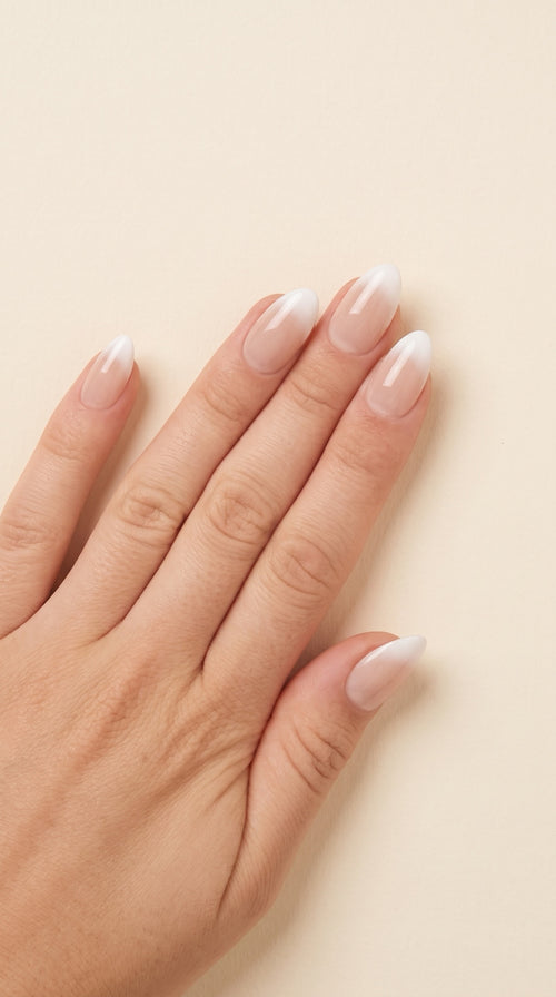 Caramel press-on nails worn on hand — almond nude-to-milky ombré finish